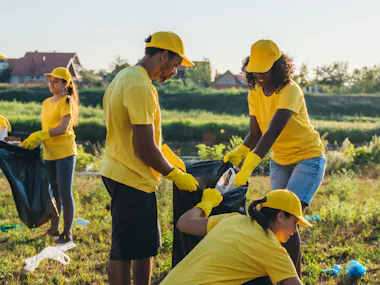 Men and woemn cleaning up grassy area.