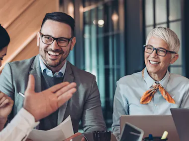 Man and woman smiling while talking to another person.